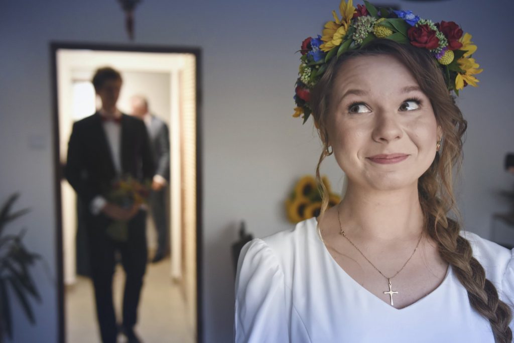 Portret panny młodej tuż przed ceremonią ślubną, wianek z kwiatów i delikatne emocje, reportaż ślubny