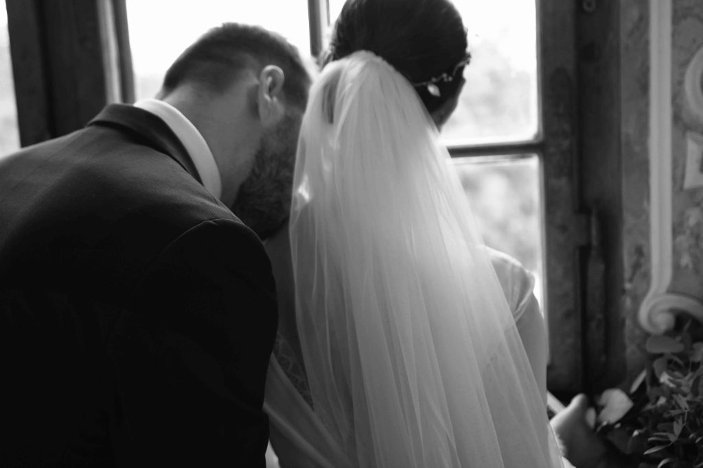 Artystyczna fotografia ślubna w pałacu – para młoda przy oknie, czarno-biała sesja ślubna