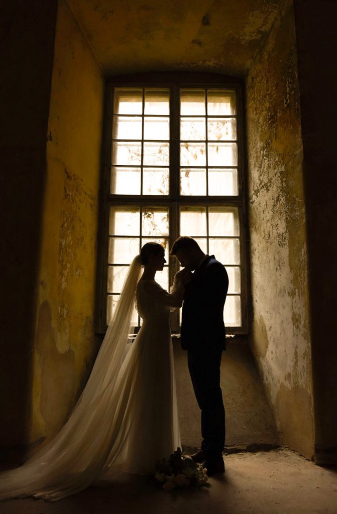 Reportażowa fotografia ślubna – panna młoda przy oknie, nastrojowe światło