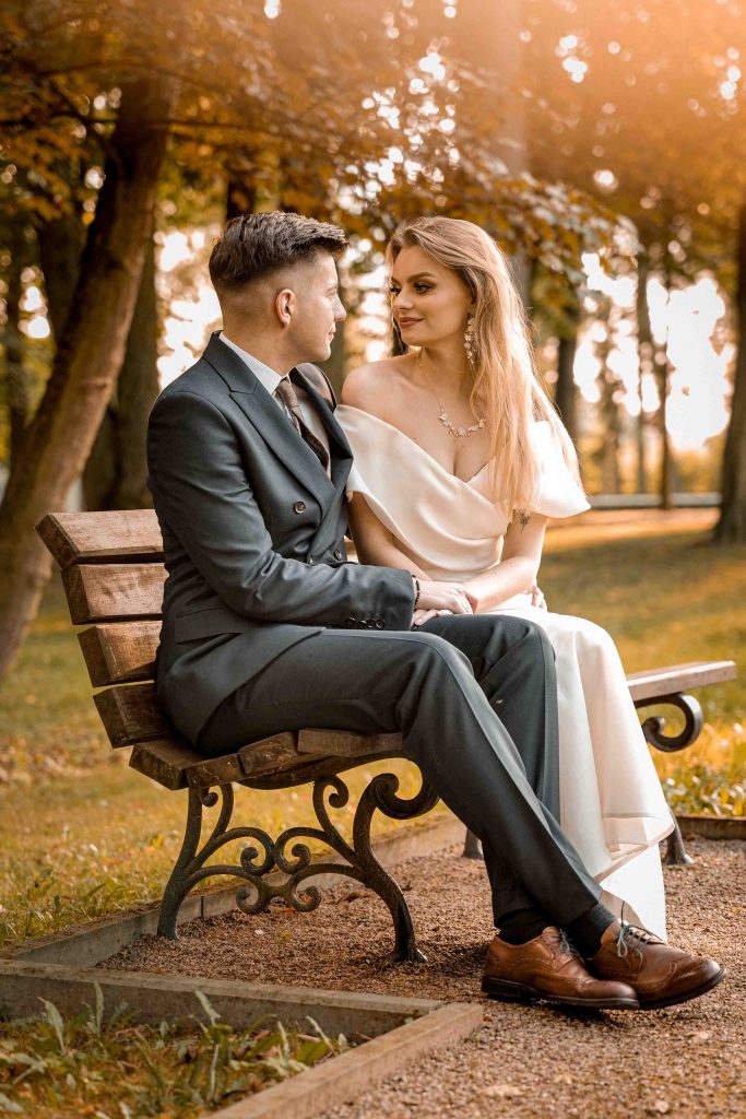 Sesja plenerowa w dworku – romantyczny portret pary młodej na ławce w jesiennym parku
