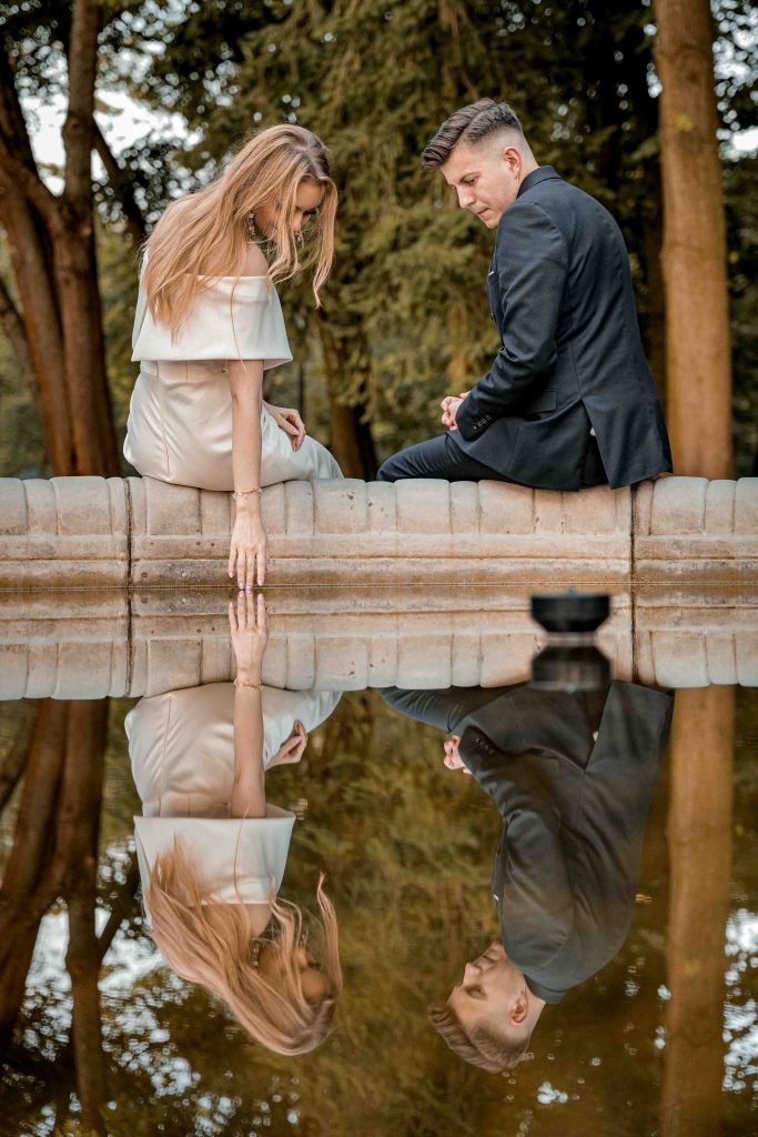 Sesja plenerowa w dworku – para młoda nad wodą z odbiciem w tafli, naturalna fotografia ślubna