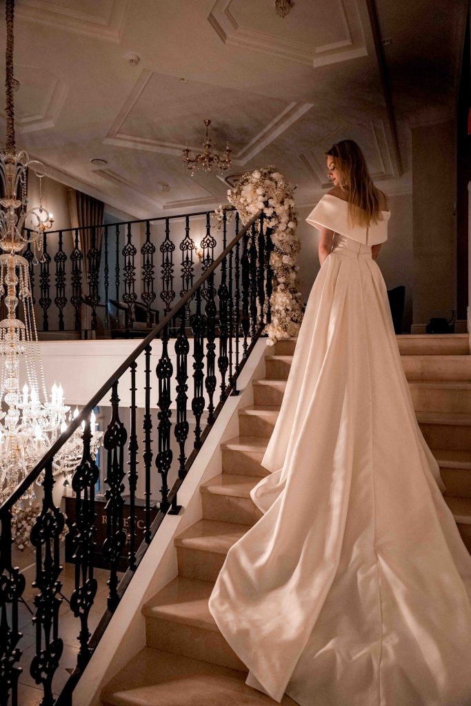 Fotografia ślubna w dworku – panna młoda na eleganckich schodach w zabytkowym wnętrzu